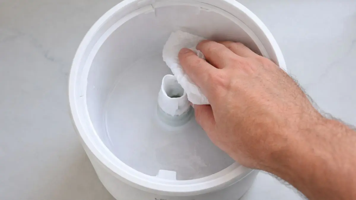 3 Proven Easy to Clean Cool Mist Humidifier Picks (2026) 3 A dad's hand wiping the inside of the wide top-fill LEVOIT Dual 200S tank with a paper towel and vinegar